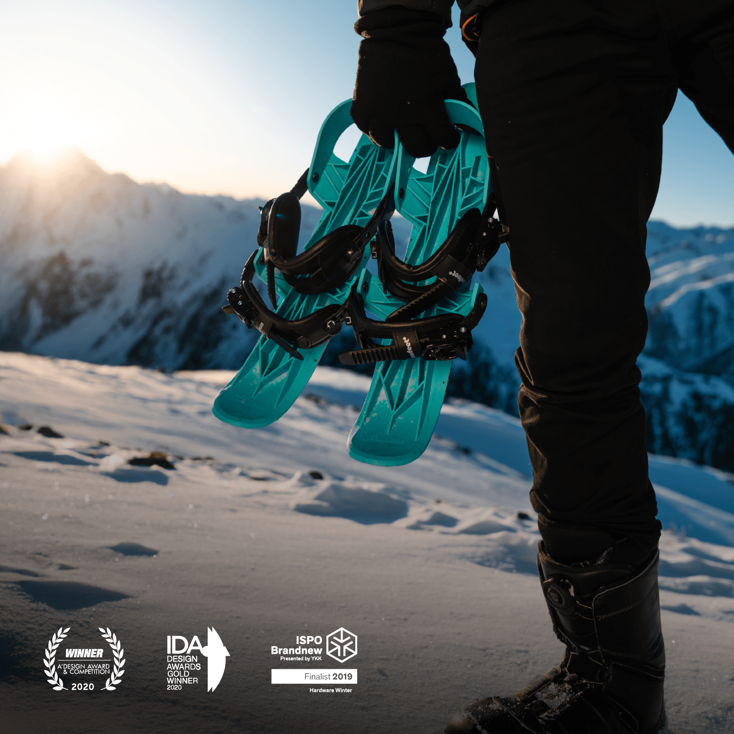 Person holding snowshoes with a mountainous landscape in the background