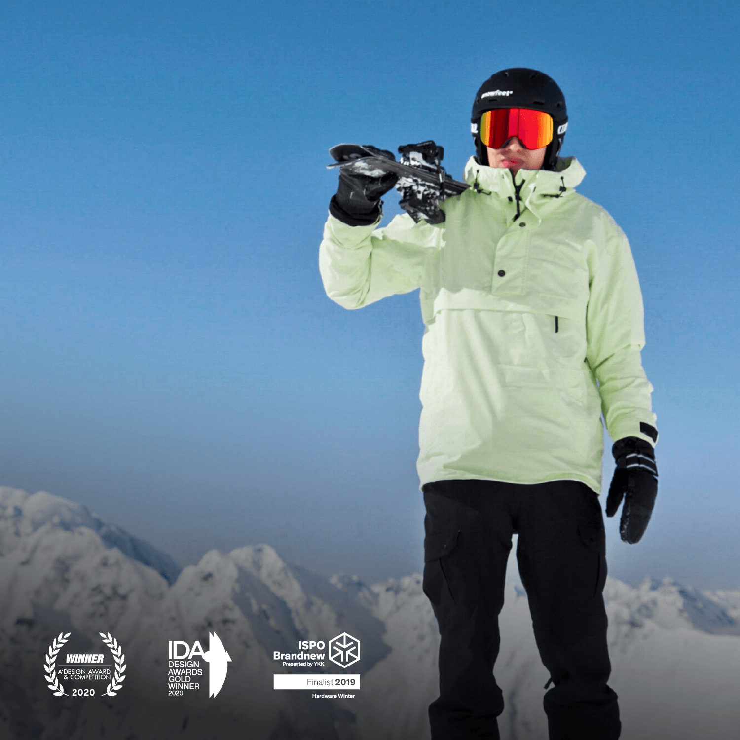 Person in ski gear holding skis against a mountainous background