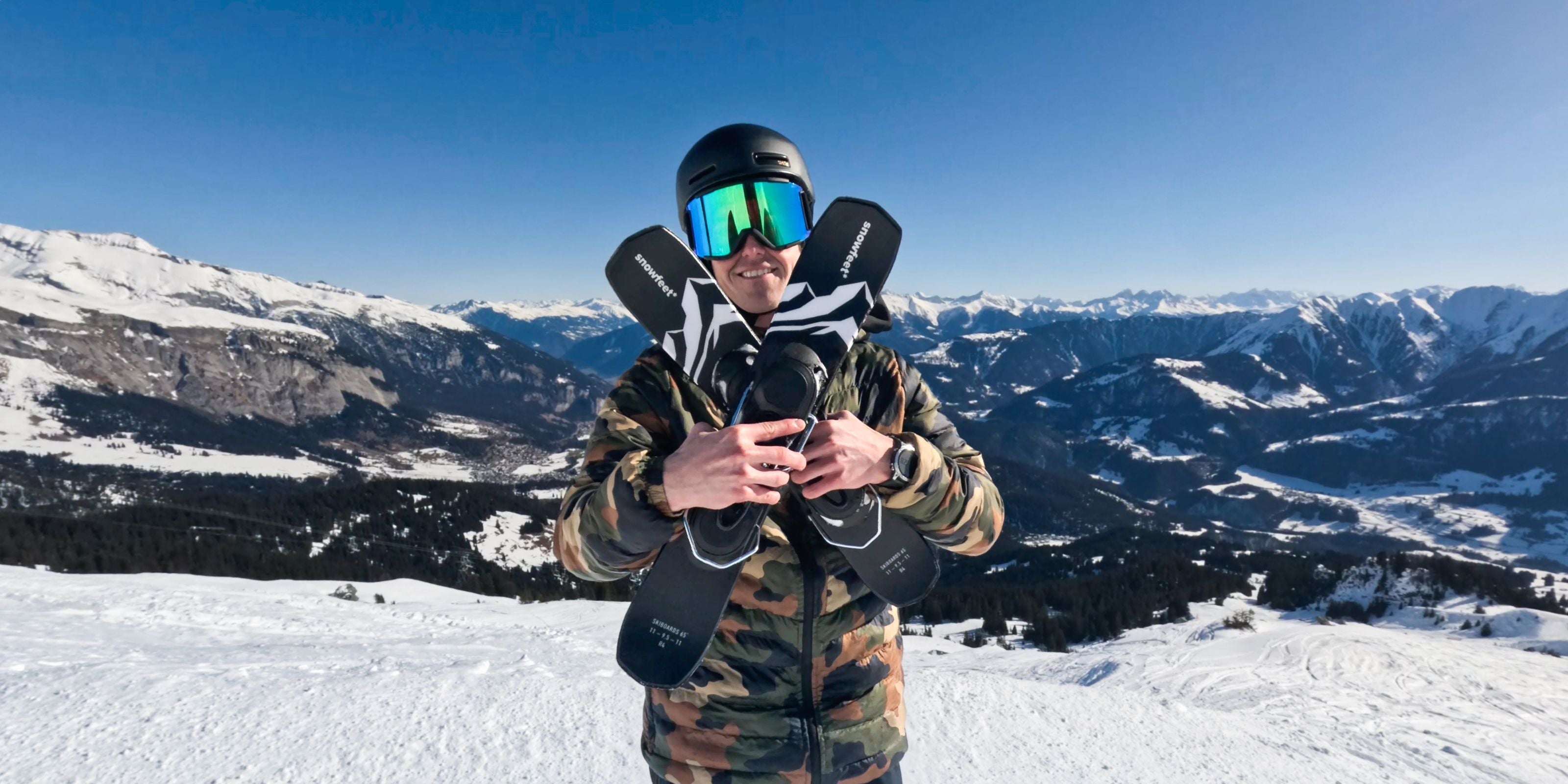 Person in winter gear with snowboard and goggles against a mountainous landscape
