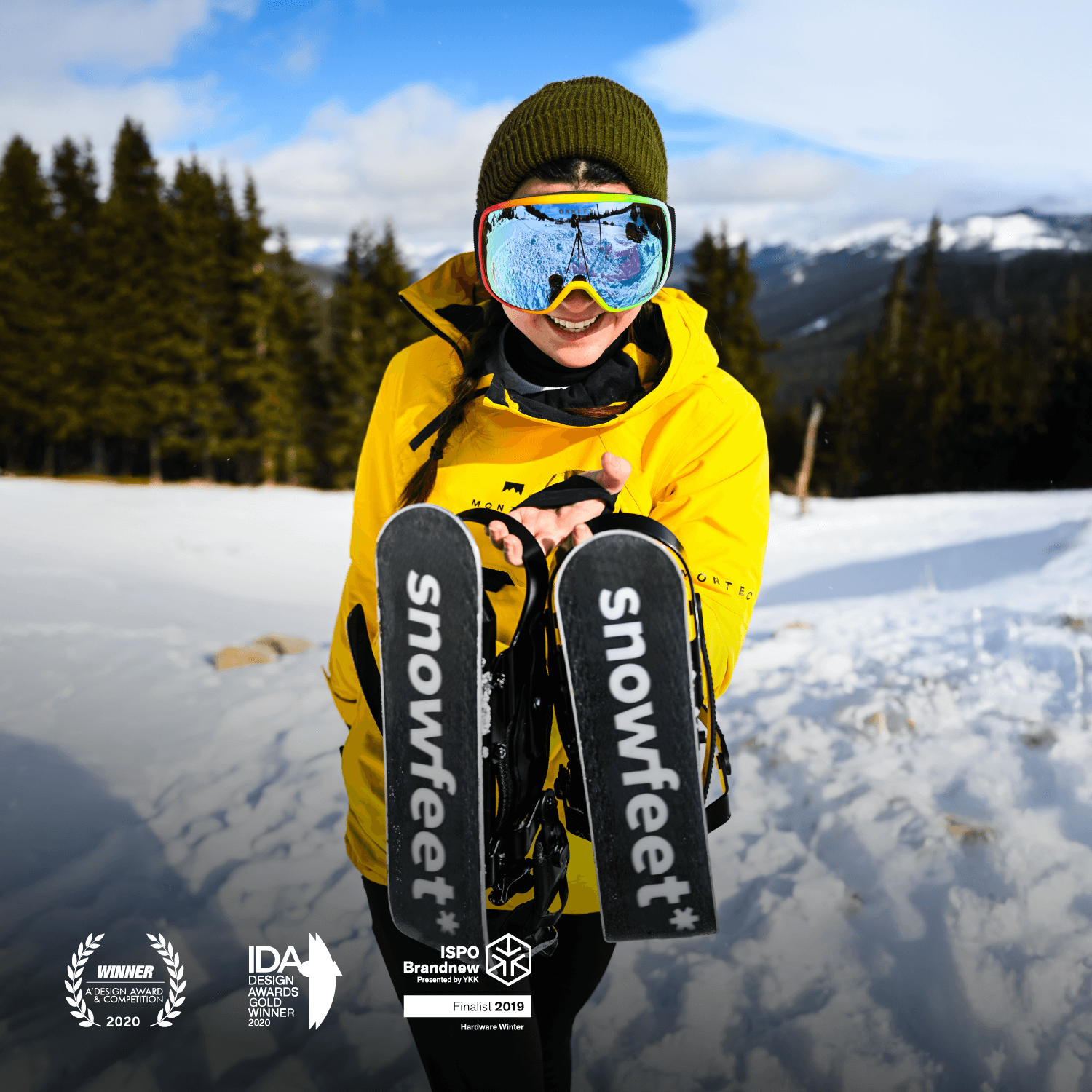 Person holding short skis with 'snowfeet' branding in a snowy landscape