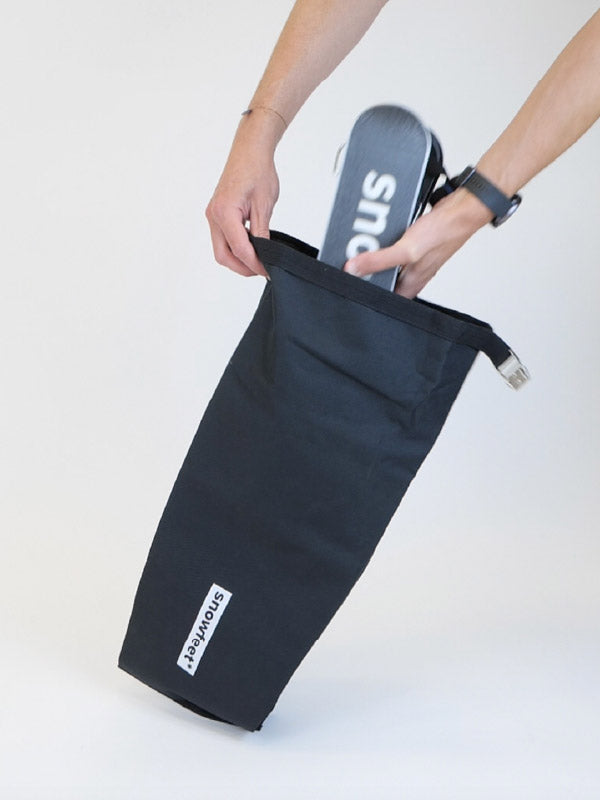 Person holding a black bag with a shoe inside on a white background