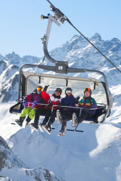 People on a ski lift with snow-covered mountains in the background