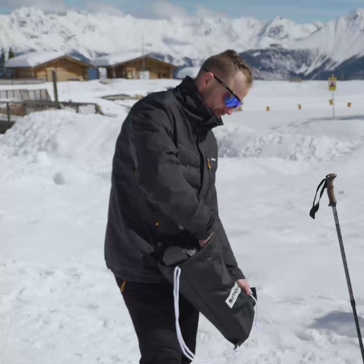 Man takes Snowfeet 50 cm short skis out of backpack, puts them on and rides down the snow